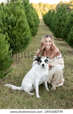 Cheerful moment at a Christmas tree farm with a woman anddog