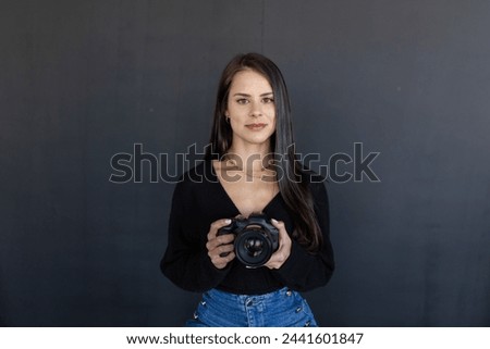 Photographer with Canon against dark backdrop.