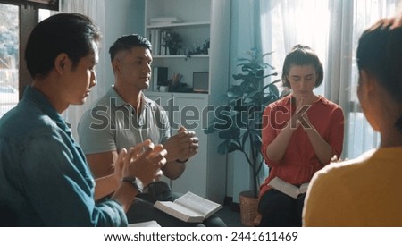 Top view of skilled diverse prayer clasping hand and praying to god while sitting at chair in circle. Top down aerial view of people folded hand while sitting with opened bible on laps. Symposium. Royalty-Free Stock Photo #2441611469