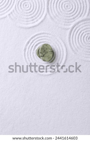 Zen garden stones on white sand with pattern, top view. Space for text