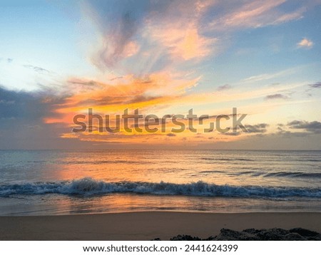 Sunset at the beach with colorful clouds and gentle waves. Seascape photography with copy space. Summer vacation and travel concept. Design for poster, banner, wallpaper.