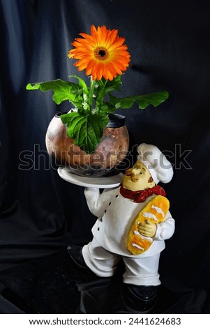 photo of orange gerbera daisy in a gourd served by a chef holding a loaf of bread