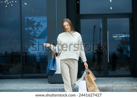 White European lady comes out of the shopping center with full bags. Beautiful woman holding shopping bags.