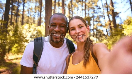 POV Shot Of Couple Hiking Along Trail Through Countryside Posing For Selfie On Mobile Phone