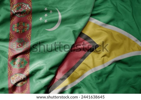 big waving national colorful flag of guyana and national flag of turkmenistan. macro