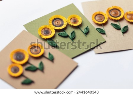 quilling card with sunflowers on brown paper background. Summer flowers. Hand made of greeting cards in paper quilling technique. Handicraft at home. Hobby, home office.
