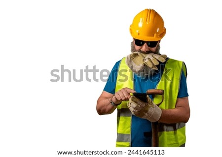 Construction worker checking mobile phone while he holds a glove with his mouth, isolated on white background