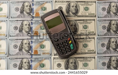 Terminal for cashless payments. Concept - refusal of cash transactions. Hundred dollar bills near cash register terminal. Concept - sale equipment for working with bank cards. Payment upon purchase Royalty-Free Stock Photo #2441655029