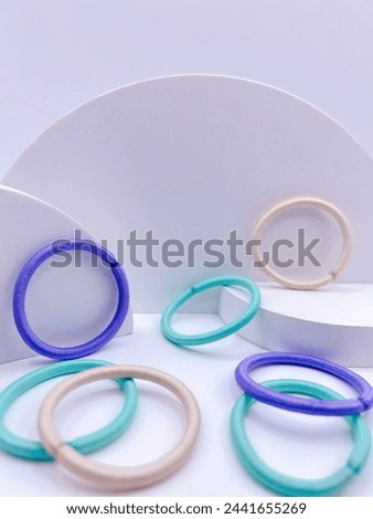 Rubber Band Circular Arrangement. Captivates with vibrant hues of blue, green, and pink against a white backdrop. Shot from a low angle, the image exudes depth and playfulness.
