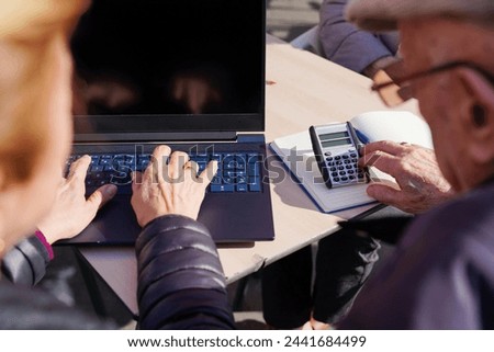 A older couple sitting with a laptop and a calculator doing the income tax