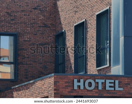 Hotel metal signage, part of building brick wall background . Iron Letters , font style . Windows glass frames.