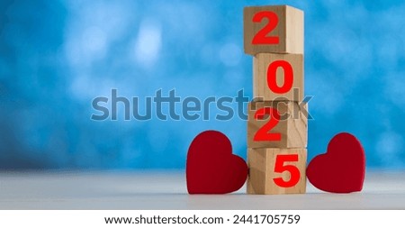 New Year text 2025 inscribed on the dice tower with two hearts. Concept of special occasions in the new year.  Royalty-Free Stock Photo #2441705759