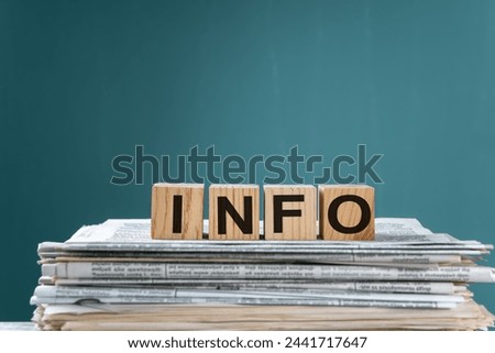 Newspapers on wooden cubes with "INFO" written on them, studio background, stock photo
