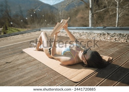 Woman reading a book on the terrace of countryside cottage