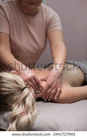 A woman undergoing a massage of the cervical-collar area. Vertical photo. 