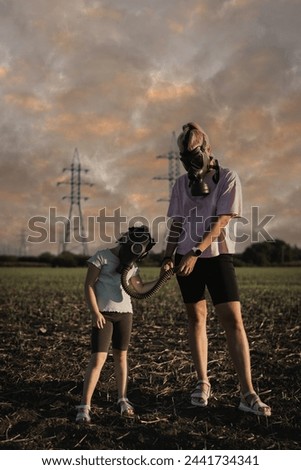 Apocalypse, end of the world, air pollution, nuclear war. Mom and daughter in gas masks in a field, the sky with poisonous clouds.  Royalty-Free Stock Photo #2441734341