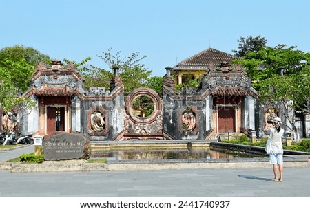 A female tourist tales a picture of Ba Mu temple gate (Cong Chua Ba Mu) in Hoi An, Vietnam, first constructed in 1626