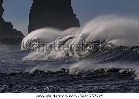 The image of a large wave crashing onto the shore is both awe-inspiring and powerful, capturing the relentless force and beauty of the ocean in motion. Royalty-Free Stock Photo #2441757225