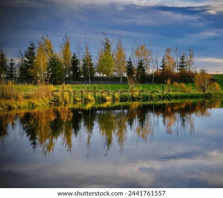 Fall scene with reflections in the pond and a stormy sky