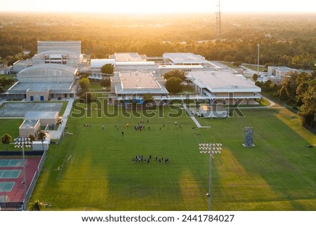 Public school sports arena in North Port, Florida with school kids playing American football on grass stadium. Outdoor activities concept Royalty-Free Stock Photo #2441784027