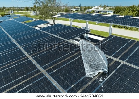 Hurricane wind damage to solar panels installed as shade roof over parking lot for parked electric cars. Failing of photovoltaic technology integrated in urban infrastructure Royalty-Free Stock Photo #2441784051