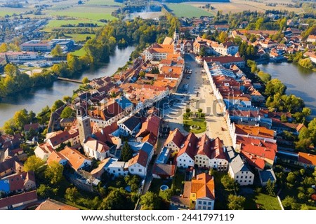 Scenic view from drone of historic part of Czech town of Telc with brownish tiled roofs of houses and medieval Castle surrounded by ponds.. Royalty-Free Stock Photo #2441797119
