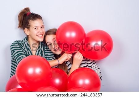 Pretty teenage girls playing with red balloons.