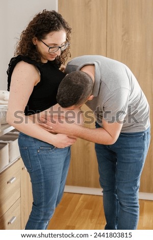 Man kissing the belly of a pregnant woman at home