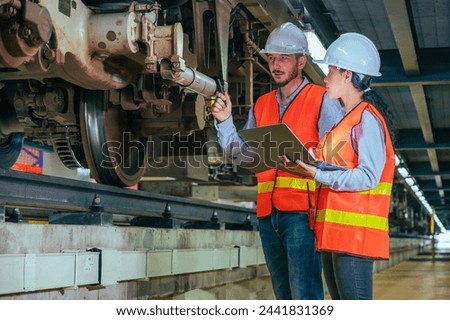 In this compelling stock photo, an engineer is captured in the dynamic environment of a train and railway garage, immersed in the meticulous tasks of maintenance, repair, or inspection.