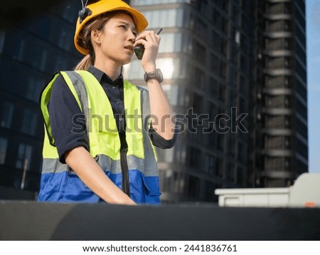 Female woman lady girl white caucasian person people human yellow orange color hardhat helmet safety industry talkie walkie radio headwear engineer safety construction occupation labor day may project Royalty-Free Stock Photo #2441836761