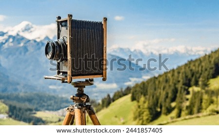 old antique bellows film camera on wooden tripod taking picture of landscape, outdoors photography, close up side view of camera