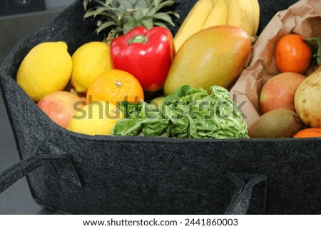 Close up of eco fruits and vegetables in a eco felt bag, on kitchen table  Royalty-Free Stock Photo #2441860003