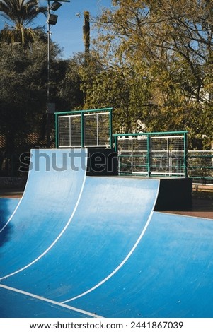 Vertical photo of a sunny day at the skate park. A vibrant blue ramp ready for action.