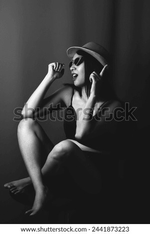 Black and white image of a young Asian woman wearing a hat and glasses. Photos in the studio