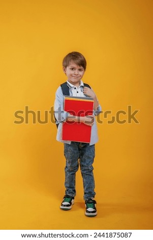 Little boy is in the studio against yellow background.
