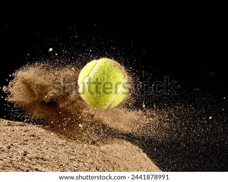 Jumping green tennis ball in dry sand explosion on black background
