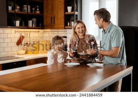 A heartwarming scene unfolds as a family relishes a mouthwatering chocolate cake together in the warmth of their sunlit kitchen, sharing smiles and creating memories Royalty-Free Stock Photo #2441884459
