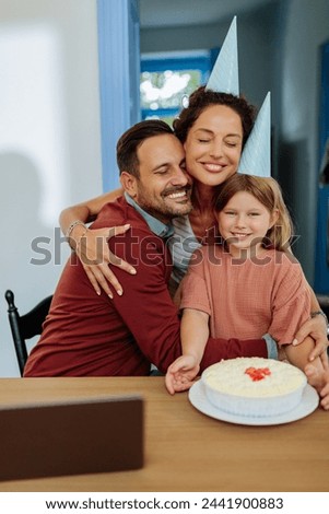 Family of three hugging, smiling and celebrating fathers birthday with a cake after he finished his work