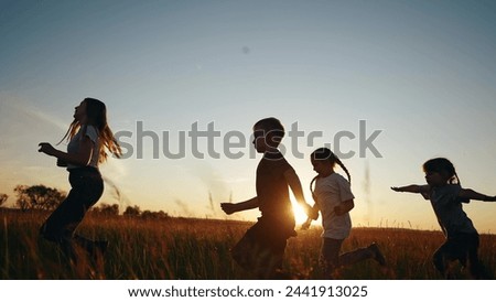 Children running in park at sunset. happy family kindergarten kids dream concept. Kids running in grass silhouette. Children lifestyle playing outdoors silhouette. Kids playing in park at sunrise