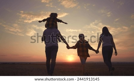 people in the park. big family silhouette walk at sunset. mom dad and daughters walk holding hands in park. large family kid dream concept. parents and children walking back fun silhouette