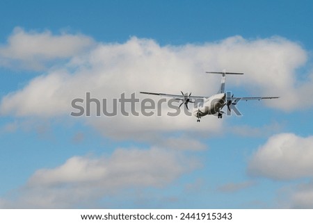 Rear view of an ATR 72 airplane among the clouds. Twin-engine turboprop short-haul regional passenger aircraft. Landing airplane. Royalty-Free Stock Photo #2441915343