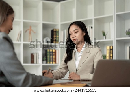 Lawyers woman and businesswoman discussing contract papers sitting at the table. Concepts of law, advice, legal service