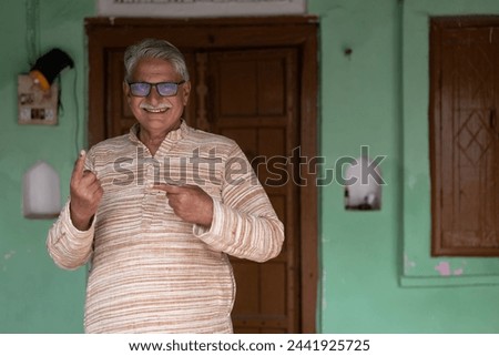 Indian senior rural man showing finger for voting Royalty-Free Stock Photo #2441925725