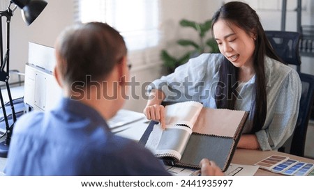 Interior designer women pointing on color swatch sample and explaining about interior design of building project to senior businessman while choosing color to designing for construction architectural.