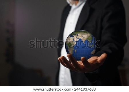 The image of a businessman with the Earth in his hand reflects the interconnectedness of business and the world.