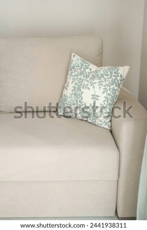 armrest of a gray sofa and decorative pillow with green leaves