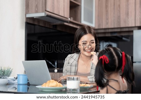 Working mom work from home office. Happy mother and daughter feed snacks to each other. businesswoman and cute child using laptop work freelancer workplace in home, Lifestyle family moment