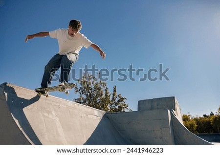 A young man doing tricks on his skateboard at the skate park. Active sport concept Royalty-Free Stock Photo #2441946223