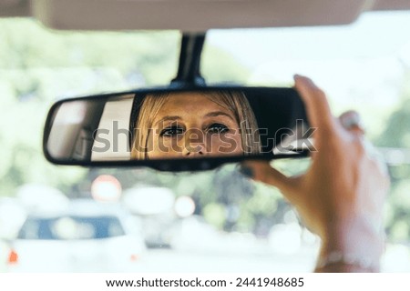 Driver woman adjusting the rear view mirror of her car.