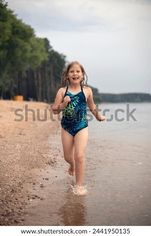 seven-year-old blonde girl runs merrily along the edge of the water, children's sports activity in summer on the water, healthy lifestyle, cheerful childhood
 Royalty-Free Stock Photo #2441950135